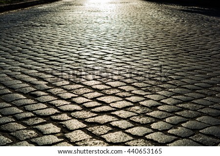 sunlight on cobblestone road in the morning. old stone texture