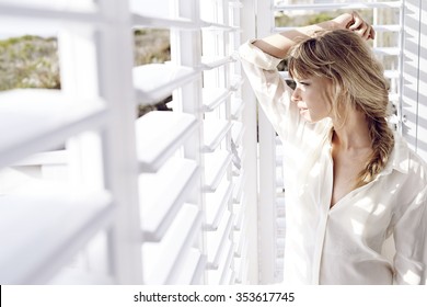 Sunlight on stunning young lady looking though shutters - Powered by Shutterstock