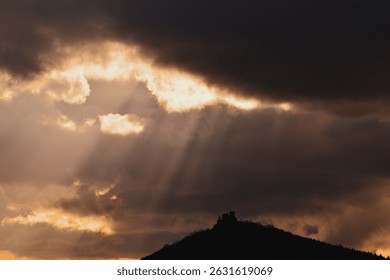 Sunlight Piercing Through Heavy Clouds Above Serene Hill Castle Ruins Czech Landscape
