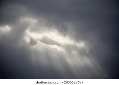Sunlight piercing through thick storm clouds creating dramatic rays.