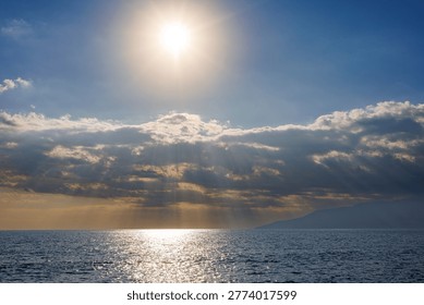 Sunlight rays piercing through clouds over calm sea