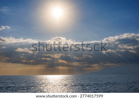 Sunlight rays piercing through clouds over calm sea