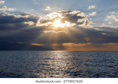 Sunlight rays piercing through dark clouds over sea