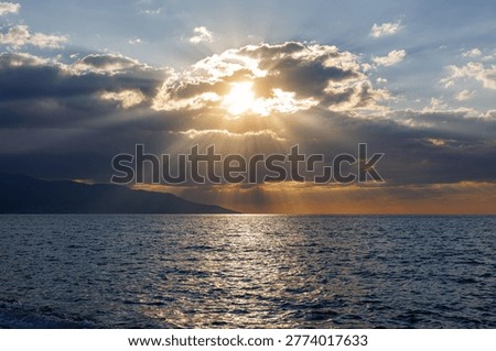 Sunlight rays piercing through dark clouds over sea