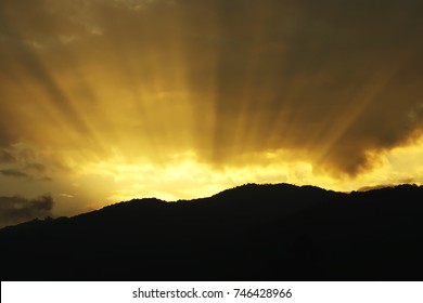 Sunlight Rays through Clouds over Mountain at Twilight