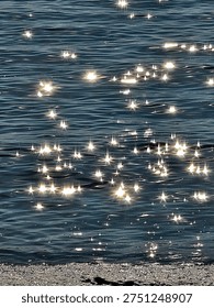 The sunlight reflecting off the waves creates a shimmering, star-like effect in the sea.