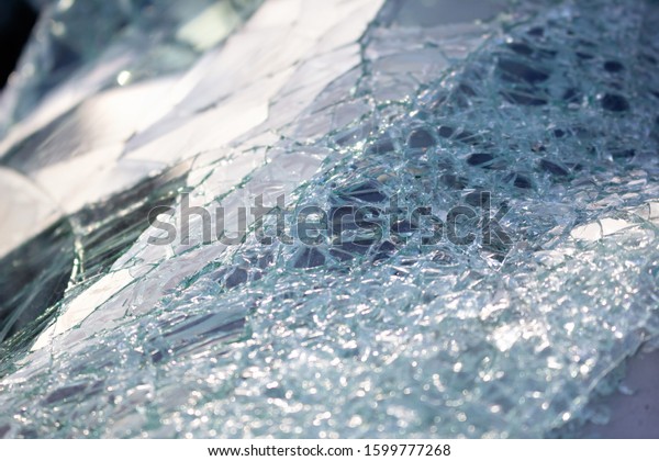 Sunlight reflects onto a damaged, shattered\
windshield of a car.