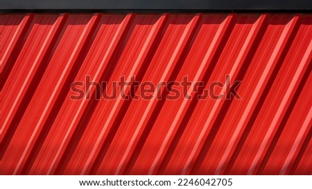 Sunlight and shadow on diagonal pattern of red Corrugated Steel fence wall with black edge