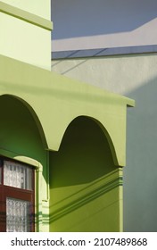 Sunlight and shadow on surface of arch awning with window on balcony of green vintage house in Tuscany style, perspective side view