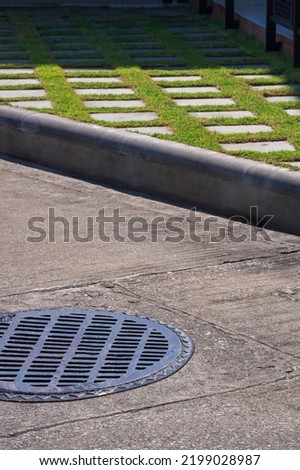 Sunlight and shadow on surface of manhole cover on street with sidewalk decorative background in vertical frame