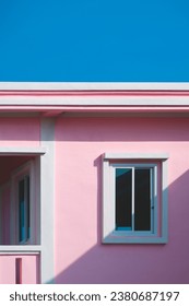 Sunlight and shadow on surface of tinted glass window on pink and white concrete wall with balcony of house building against blue clear sky in vertical frame. Exterior architecture background
