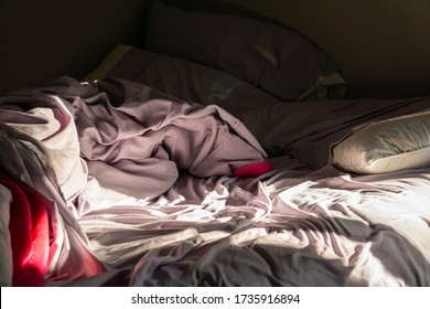 A Sunlight Shine Trough The Window On A Very Messy Bed Full Of Crumple Blanket, Pillows On The Wrinkled Bedsheet In Untidy Bedroom. Lazy To Clean Room In The Morning Concept.