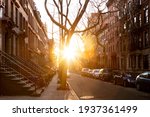Sunlight shines on a block of historic brownstone buildings on Perry Street in the West Village neighborhood of New York City NYC