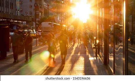 Sunlight shines on the diverse crowds of people walking down the busy sidewalk on 34th Street through Midtown Manhattan in New York City NYC