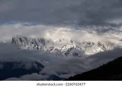 Sunlight shining through clouds on snow-covered mountains
