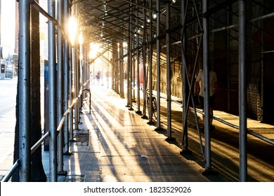 Sunlight Shining Through Construction Scaffolding Above An Empty Sidewalk In Manhattan, New York City NYC