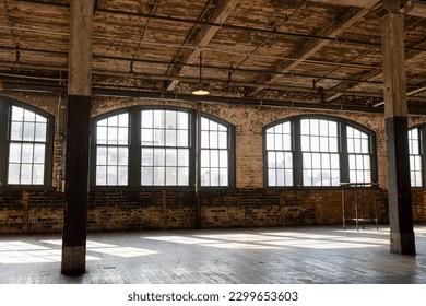 Sunlight Shining through Loft Windows casting Shadows.  One pendant light and one high top table fill the space.  Both the floor and ceiling are aged wood plank.
