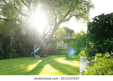 Sunlight shining through trees in backyard with treehouse and slide. Nature, sunshine, playground, leisure, outdoors, tranquility - Powered by Shutterstock