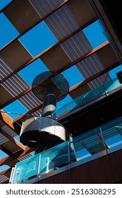 Sunlight streaming through skylight over contemporary spiral staircase with modern architectural layout and clear blue sky in backdrop