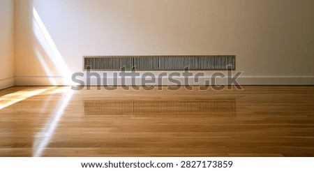 Sunlight streams across a clean, empty room, illuminating the polished hardwood floor and a long wall vent.