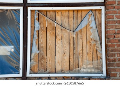 Sunlight streams through a broken window, showcasing wooden planks and a rustic brick wall in a deserted location