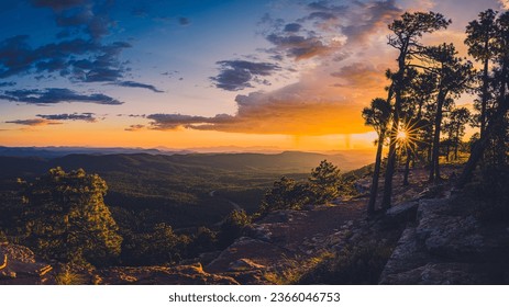 Sunlight streams through the trees as a late summer storm crosses the horizon at the Mongollon Rim