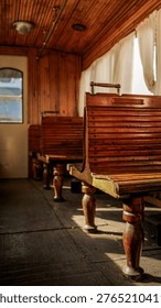 Sunlight streams through the windows of an old-fashioned train car, illuminating rows of empty wooden benches