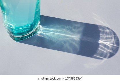 sunlight through glass of blue color water make a beautiful pattern due to light refraction on white background.