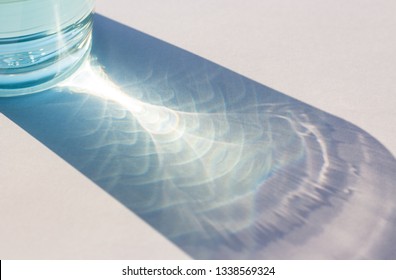 sunlight through glass of water make light and shadow on white background.