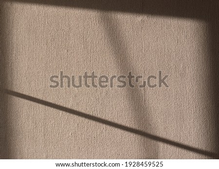 Sunlight from the window falls on the wall, decorated with a rough cloth. Abstract shadow sketch. Monochrome sepia background with copy space.

