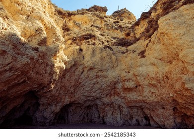 Sunlit cliffs with rugged textures and natural formations at praia da rocha, portugal, showcasing the beauty of coastal geology. - Powered by Shutterstock