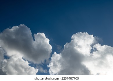 Sunlit clouds on blue sky background. Cumulus clouds against the sun - Shutterstock ID 2257487705