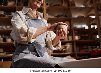 Sunlit cropped shot of creative senior woman holding clay ball in hands enjoying pottery class in art studio copy space - Powered by Shutterstock