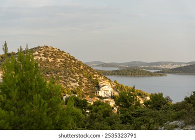 Sunlit Mediterranean hillside village with panoramic view of coastal islands and calm sea on a peaceful summer evening. Concept of serene coastal living, beautiful landscape, and natural harmony. - Powered by Shutterstock