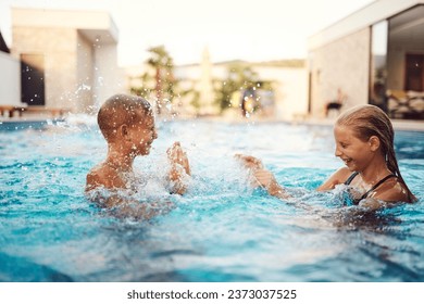 In a sunlit modern villa, a young brother and sister joyfully splash and play in the pool, basking in the warmth of a perfect summer day - Powered by Shutterstock