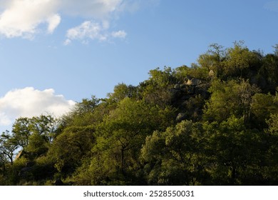 A sunlit mountain peak rises sharply against a clear blue sky - Powered by Shutterstock