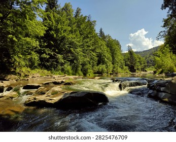 Sunlit Mountain River Cascading Through a Rocky Forest Gorge