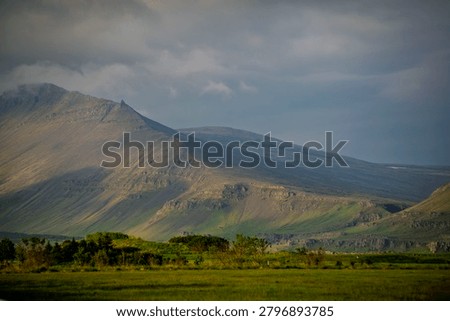 Sunlit Mountain Slopes Under Dramatic Clouds In Akranes Iceland