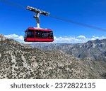 A sunlit panoramic view of Copper Canyon, with a cable car full of tourists capturing moments against the sprawling natural vista, under a nearly clear sky, with no identifiable traces of individuals 