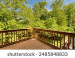 Sunlit Wooden Deck With Distinctive Wooden Railings Overlooks Lush Greenery