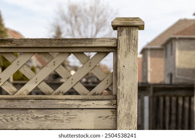 Sunlit wooden fence with lattice design - weathered texture and grain visible - suburban backdrop with houses - Powered by Shutterstock