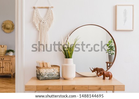 Sunny boho interiors of apartment with mirror, dressing table, furnitures, flowers, plants, rattan box, books, sculpture, macrame and design accessories. Stylish home decor of open space. Template. Stock photo © 