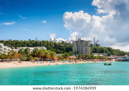 Sunny Caribbean beach, palm trees in resorts and turquoise sea in Montego Bay, Jamaica island.
