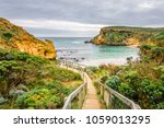 Sunny cloudy summer coast view to the wild wave Bass Strait with beautiful sandy beach path and rocky erosion cliffs of the Great Ocean Road limestone formations Childers Cove, Warrnambool,  Australia