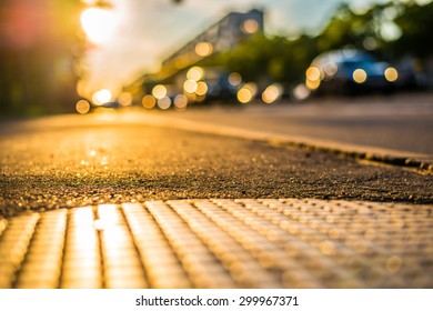 Sunny Day In A City, View From The Sidewalk At The Hatch At The Passing Cars On The Highway