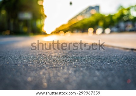 Sunny day in a city, view from the sidewalk level to the stream of cars