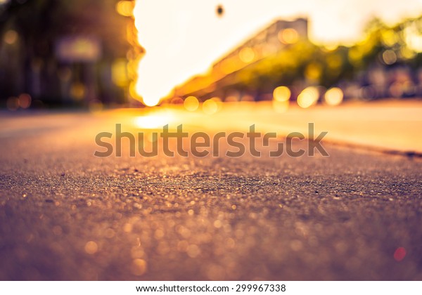 Sunny day in a city,\
view from the sidewalk level to the stream of cars. Image in the\
orange-purple toning