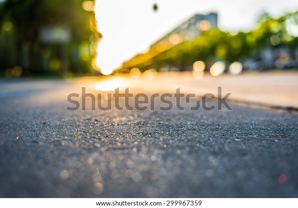 Sunny day in a city, view from the sidewalk level to\
the stream of cars