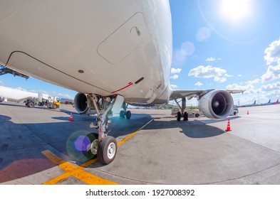 Sunny day and glare at the airport, view of the aircraft front landing gear and wing
