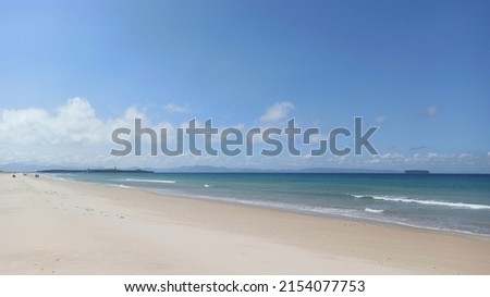 Sunny day at Los Lances beach in Tarifa (Cádiz). Coast of golden sand bathed by waters of the Atlantic Ocean. The sky is blue with little cloudiness and the water is calm.